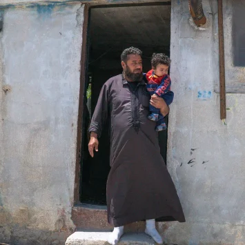 Walid y su hijo menor fuera de su refugio en el campamento de Al-Kuwaiti, Idlib, al noroeste de Siria.