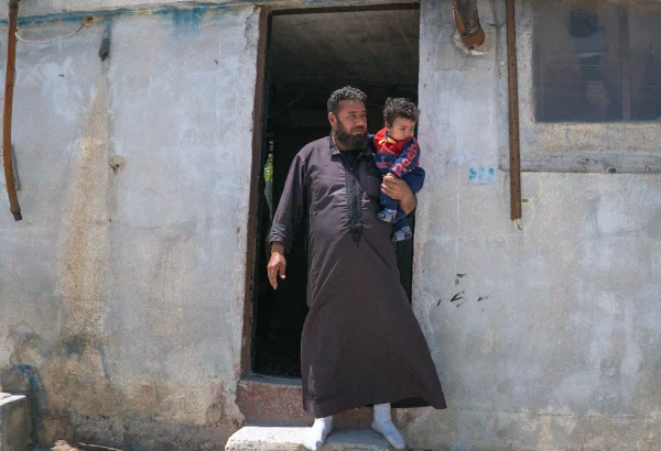 Walid y su hijo menor fuera de su refugio en el campamento de Al-Kuwaiti, Idlib, al noroeste de Siria.