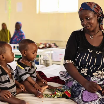 Binta Abdulraziqu junto a sus hijos gemelos, quienes fueron ingresados ​​por desnutrición aguda grave en el centro de nutrición terapéutica para pacientes hospitalizados de Maiyama. Estado de Kebbi, Nigeria, agosto de 2025.