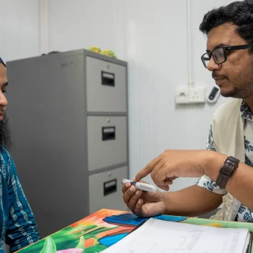 Un paciente con diabetes recibe atención médica. El médico de MSF le muestra una pluma de insulina.