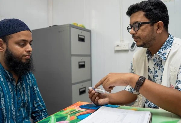 Un paciente con diabetes recibe atención médica. El médico de MSF le muestra una pluma de insulina.