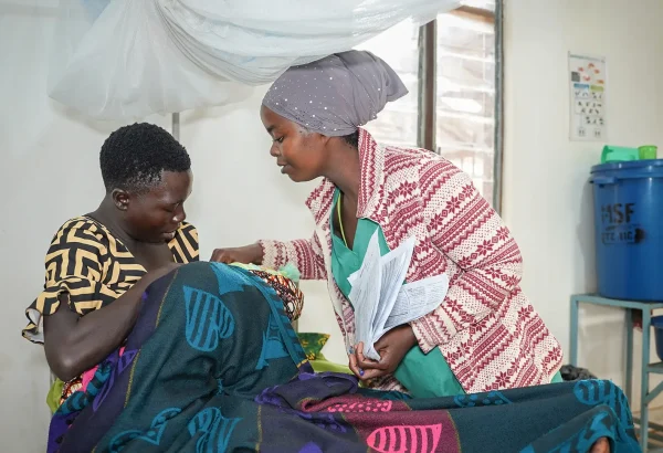 Una enfermera auxiliar de MSF y una madre atienden a un bebé en la sala de maternidad del hospital de MSF en el campo de Nduta.