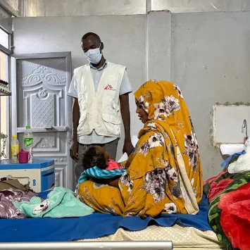 Ferdos Salih sostiene a su bebé de 11 meses, Banan, quien padece sarampión, en la sala de aislamiento del Hospital Universitario El Geneina, con apoyo de MSF. Sudán, diciembre de 2025.