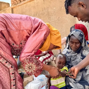 Un voluntario comunitario y un miembro del personal de MSF realizan un cribado MUAC, en Mohamed Ayoub, de 18 meses, inmediatamente después de su vacunación contra el sarampión.