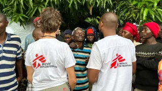 El personal de MSF Nathalie Gielen y Gimo Lazimo hablan con un grupo de personas desplazadas que esperan fuera de una clínica móvil de MSF en Alua Velha, distrito de Eráti, provincia de Nampula.