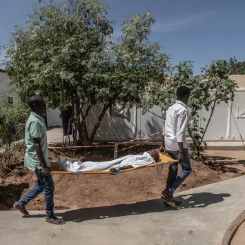 Dos trabajadores médicos de MSF transportan a un niño pequeño en una camilla desde el quirófano hasta la unidad de cuidados intensivos del Hospital París gestionado por MSF en Tawila.